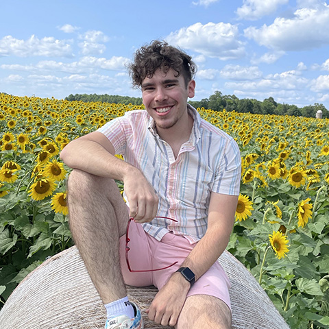 Harrison Bouche, sitting on a hay bale in a sunflower field
